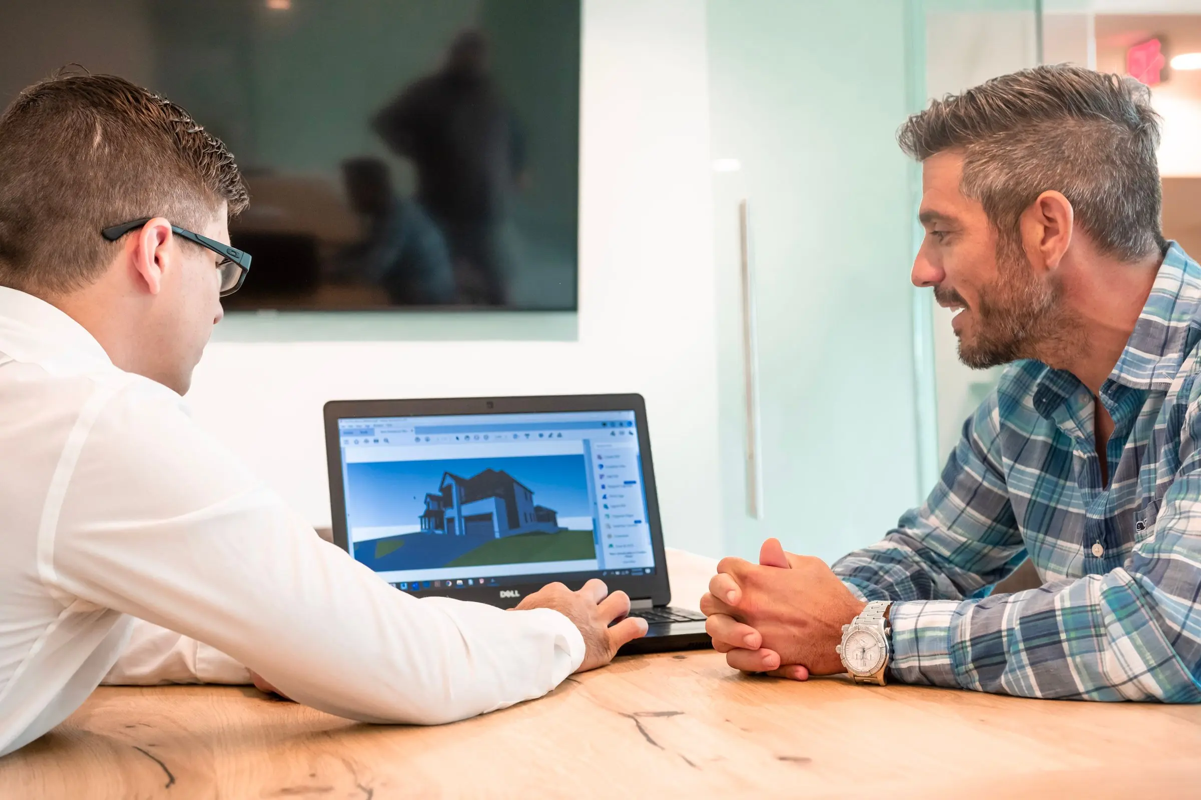 Two people reviewing a design on a laptop across a desk